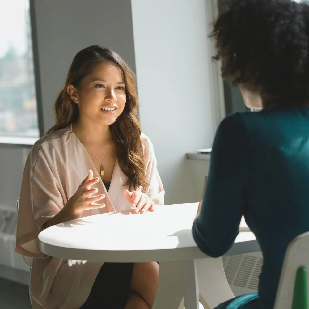 Two professional women having a face-to-face discussion about work, represent a talent and an employer.